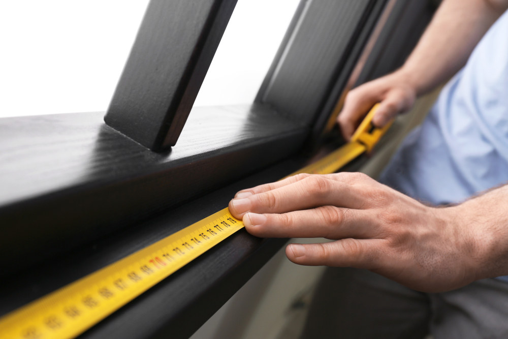 Man measuring window frame indoors